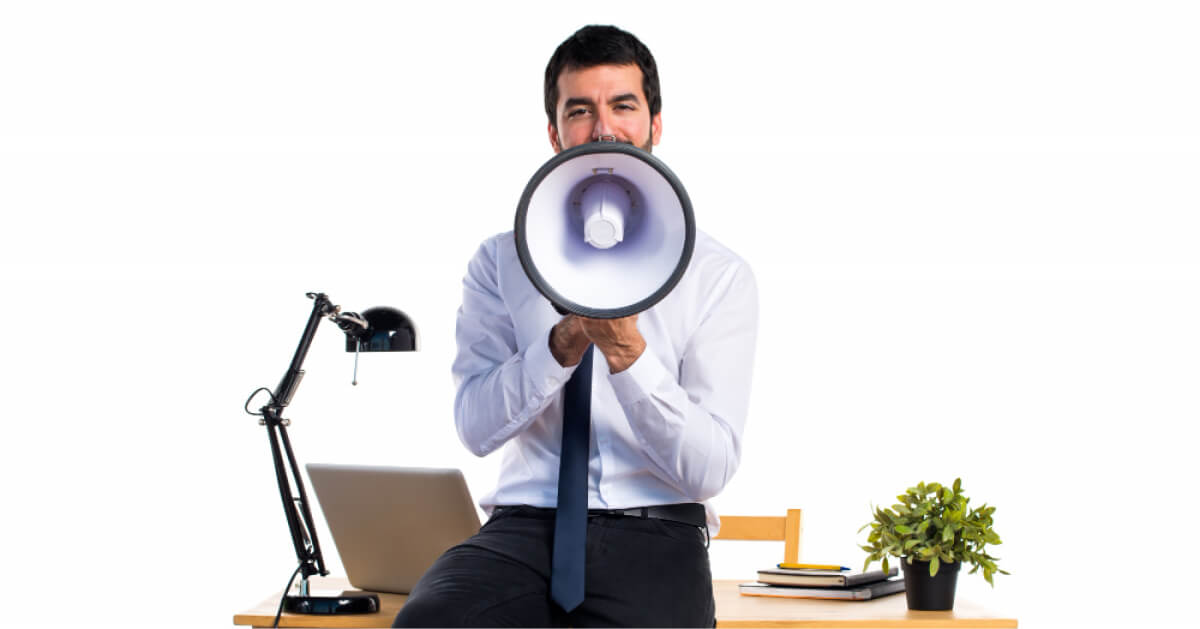 Man holding a microphone in front of an office desk